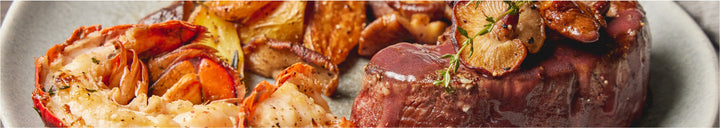 Lobster tail, filet mignon and fried potato wedges on a plate
