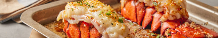 Two cooked lobster tails in pan